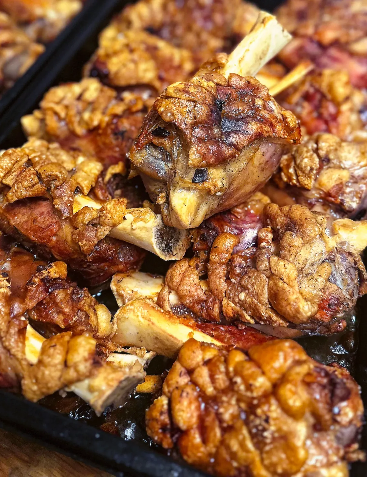 Knusprige Schweinshaxn mit goldbrauner Kruste auf dem Ofenblech